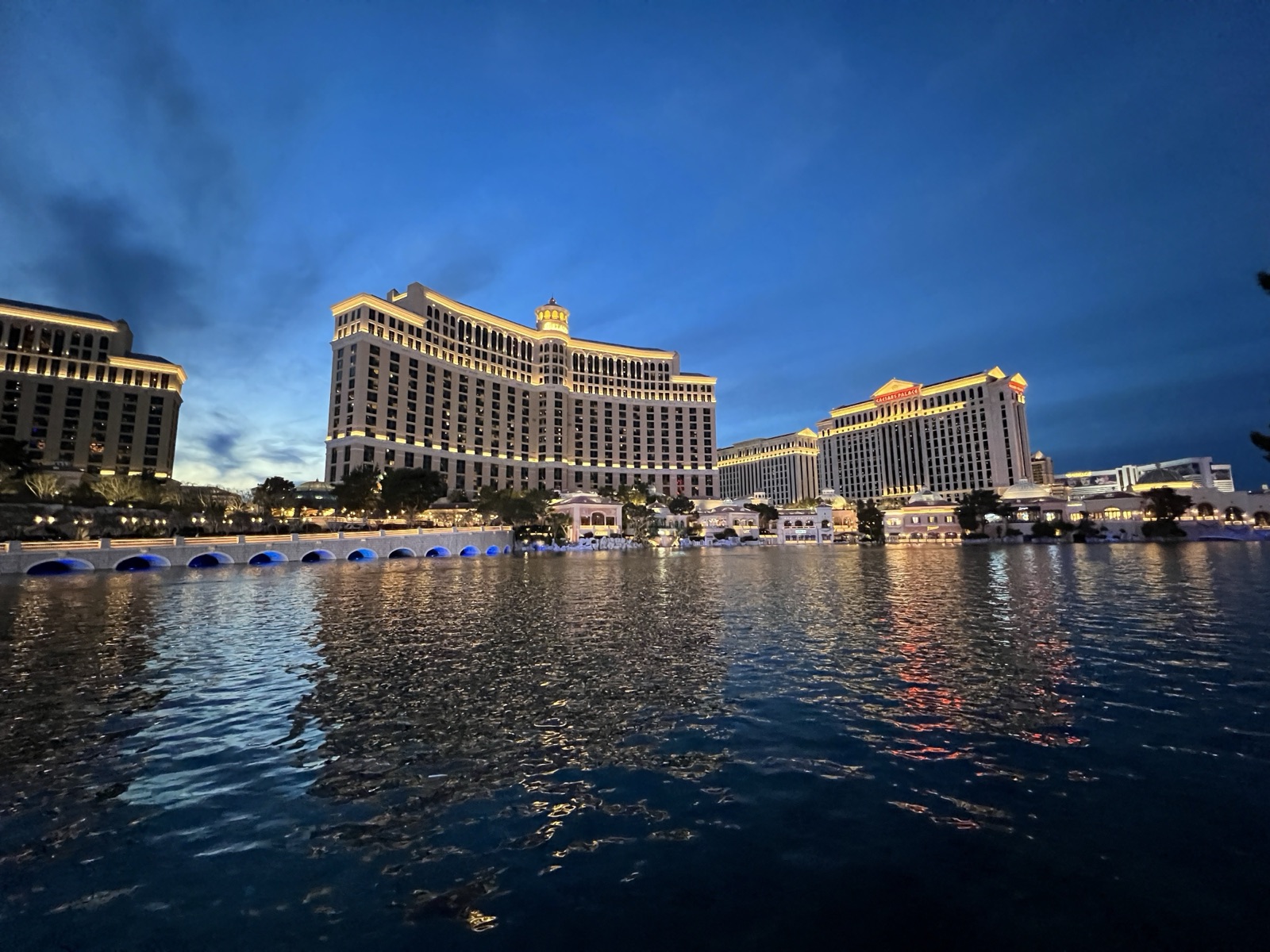 Bellagio and its fountain lake at blue hour, seen from Las Vegas Boulevard with Caesars Palace to the right