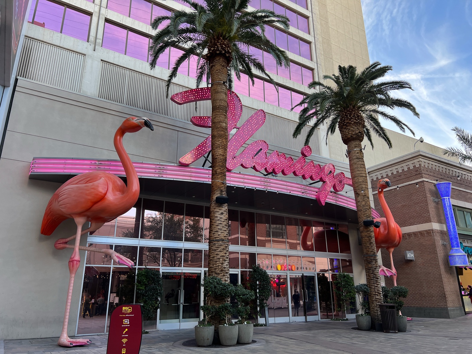 The pink Flamingo Las Vegas entrance sign with flamingo sculptures and palm trees