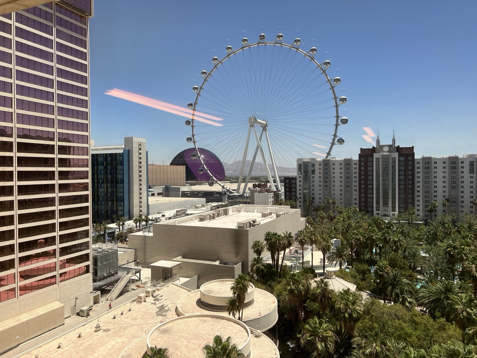 The High Roller observation wheel in daylight with the Sphere behind it, seen from a Flamingo tower