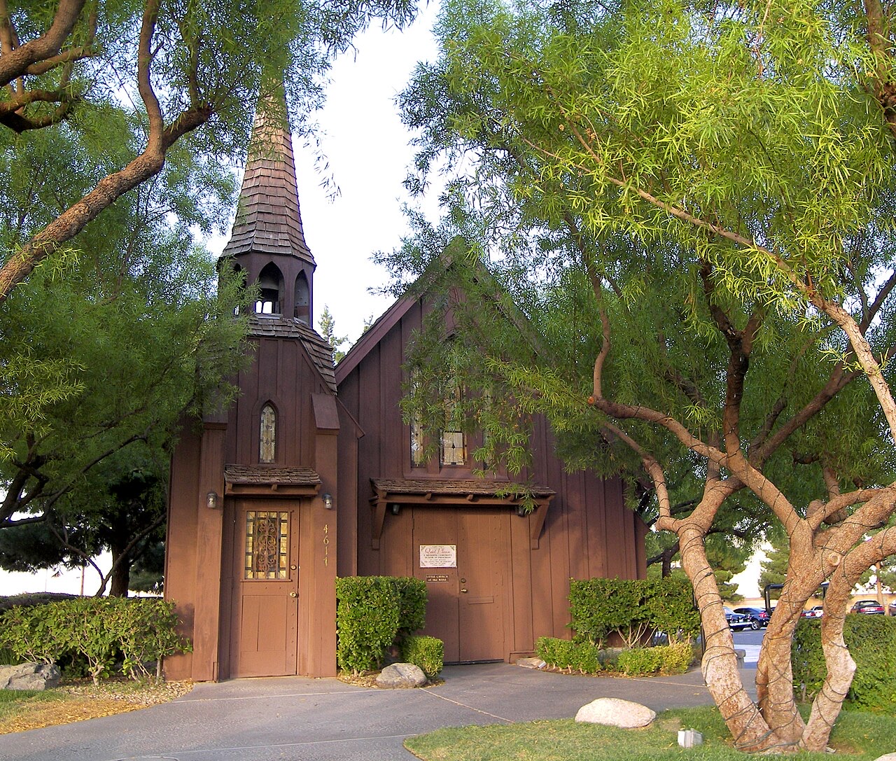 Front of the Little Church of the West, a wooden chapel with a bell tower, framed by trees on the South Strip